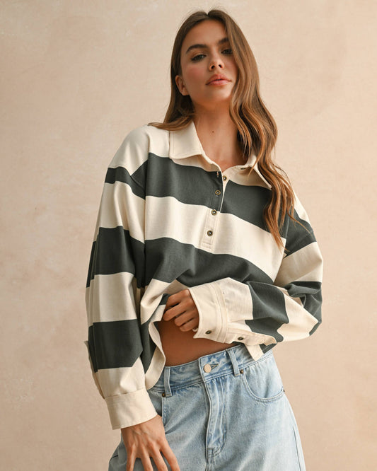 Woman wearing a green and white striped shirt with light blue jeans on a beige background