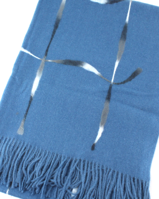 A blue knit scarf with fringe along one end, featuring a metallic silver abstract line pattern across the front, shown on a plain white background.