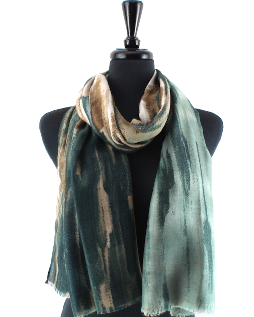A lightweight scarf with a green and beige abstract tie-dye pattern, draped on a black mannequin torso against a white background.