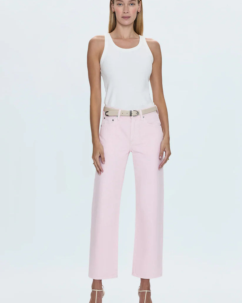 Model wearing pink jeans and white tank top in front of a white background