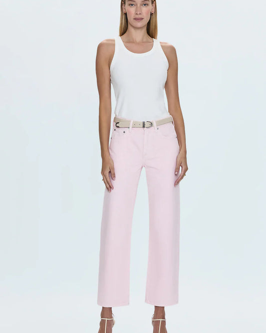 Model wearing pink jeans and white tank top in front of a white background