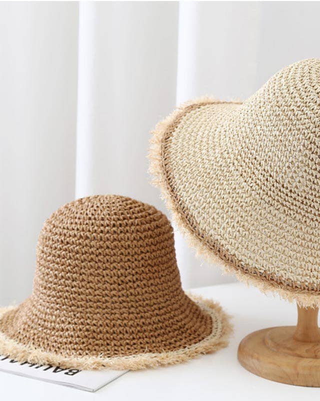 Two straw hats on a white surface with a neutral background