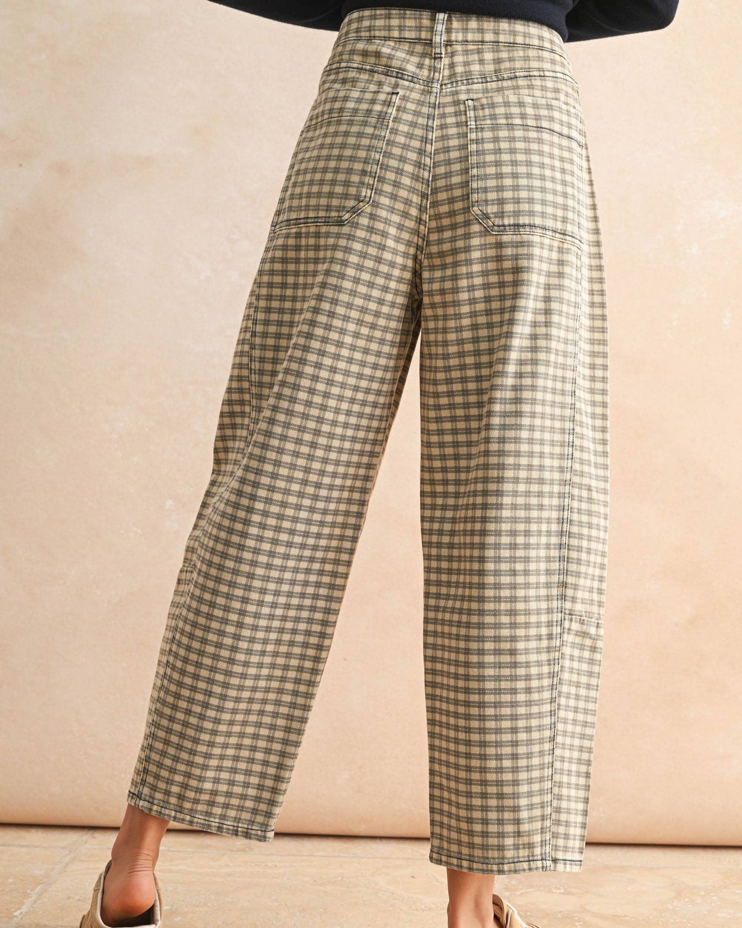 Person wearing plaid pants on a beige background