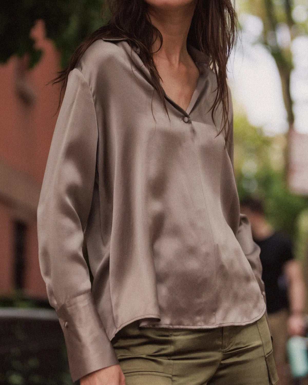 Person wearing a beige blouse and green pants outdoors