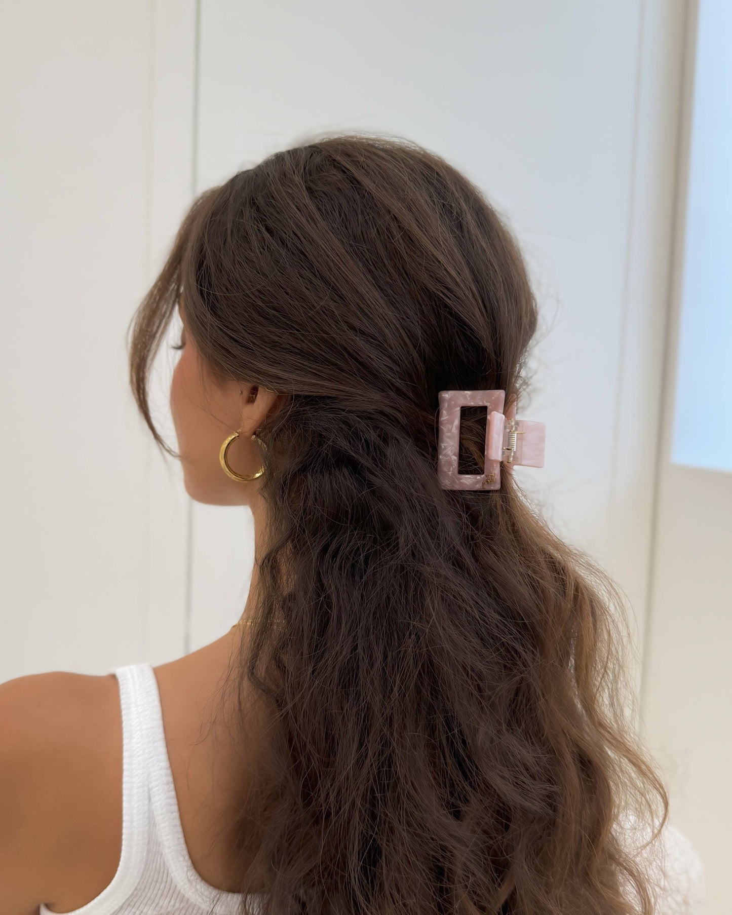 Person with long hair styled with a pink hair clip against a neutral background