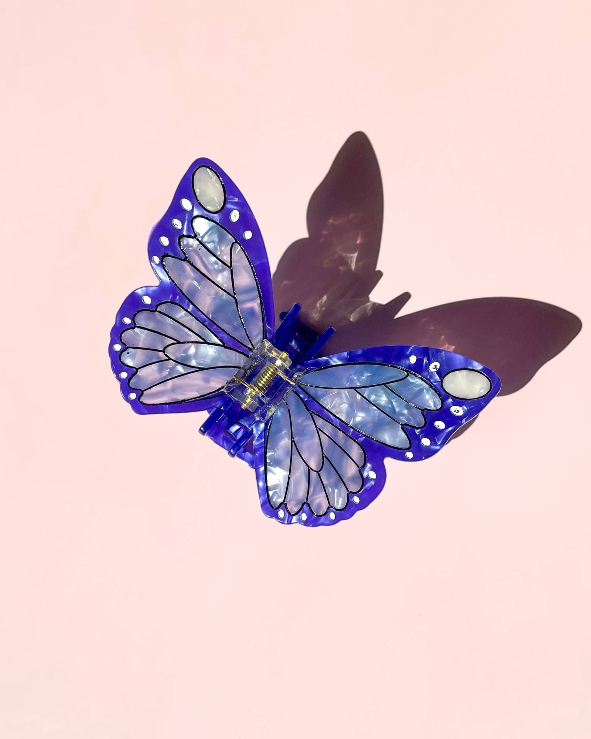 Blue butterfly hair clip on a pink background