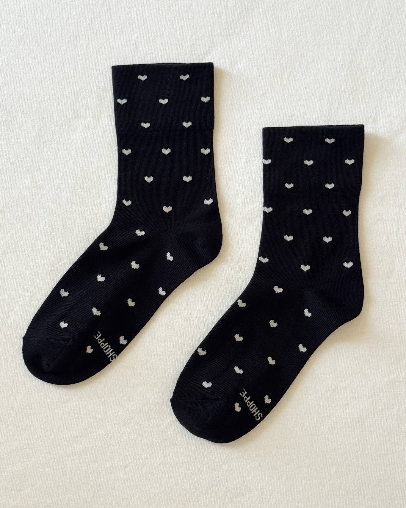 Black socks with white heart patterns on a light beige background