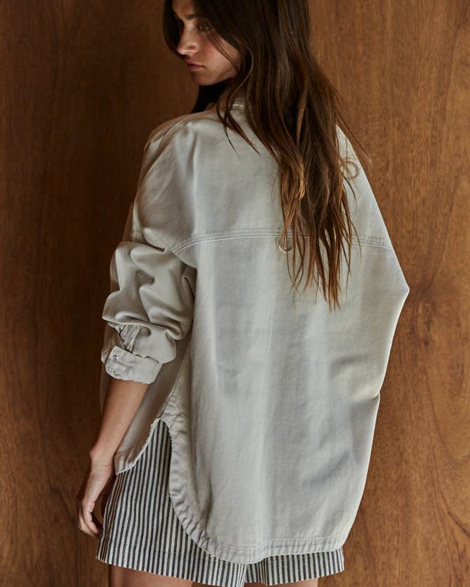 Woman wearing a light-colored shirt over a striped dress against a wooden background