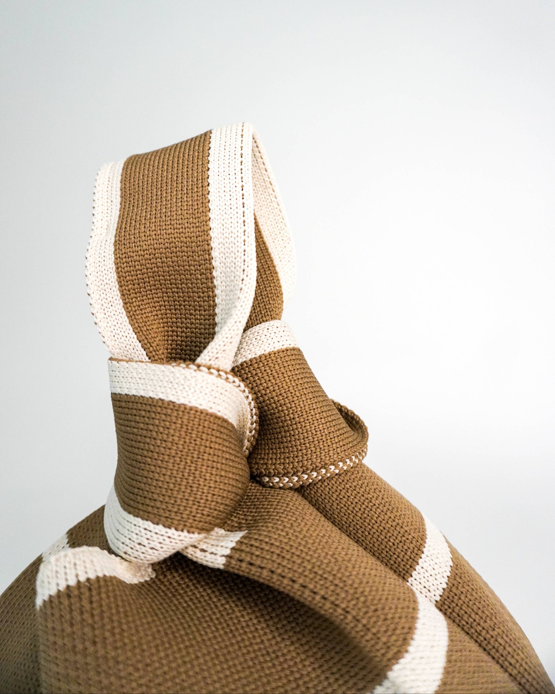 Brown and white knitted blanket on a light gray background