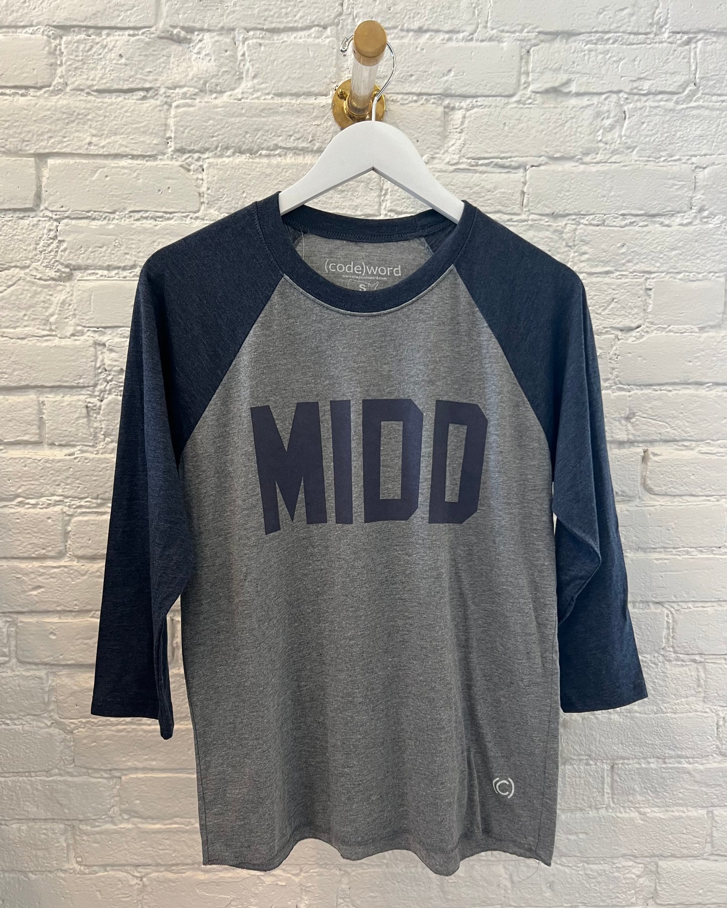 Middlebury College Baseball Tee that says MIDD on a white brick background