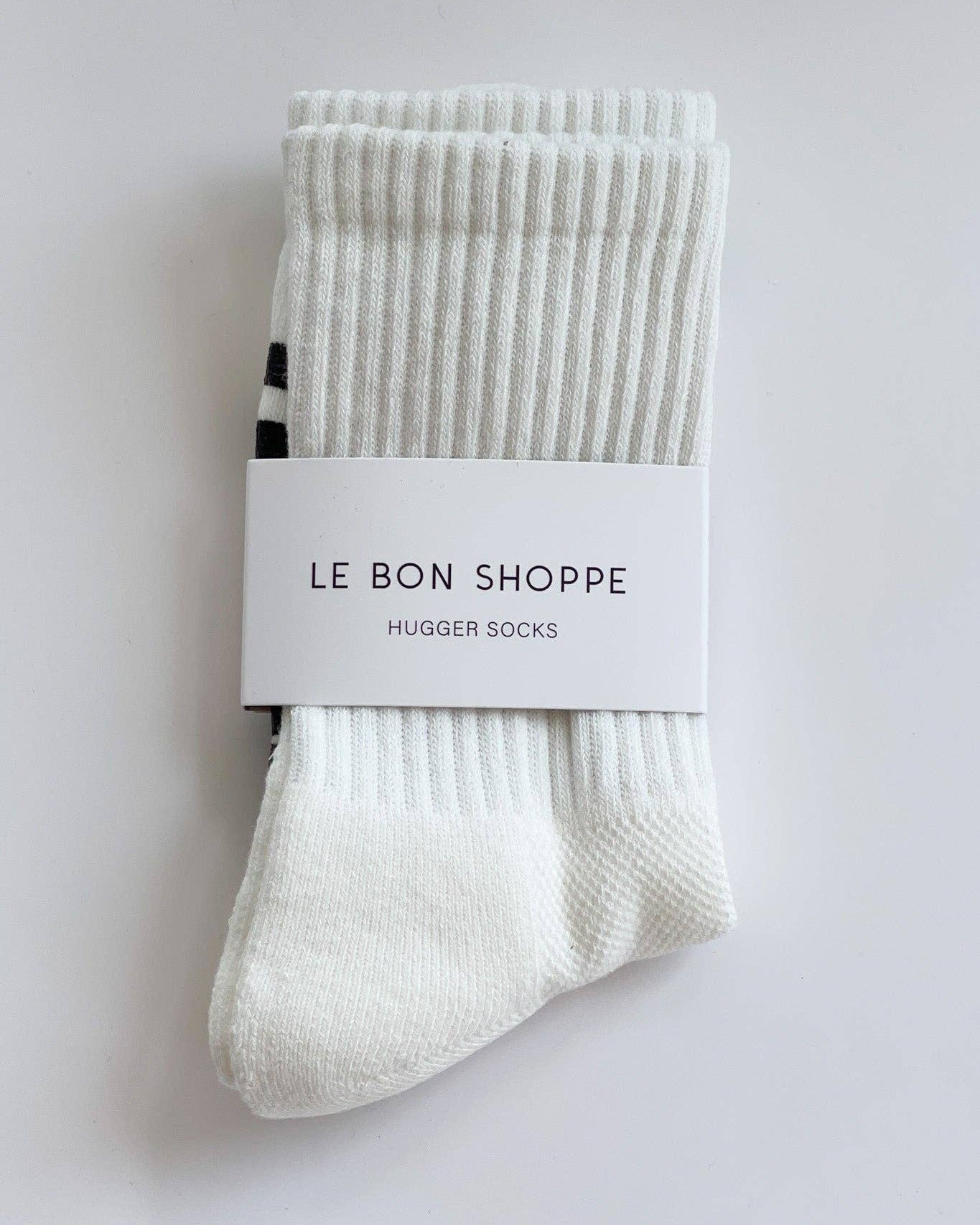 Packaged white socks with 'Le Bon Shoppe' label on a light gray background