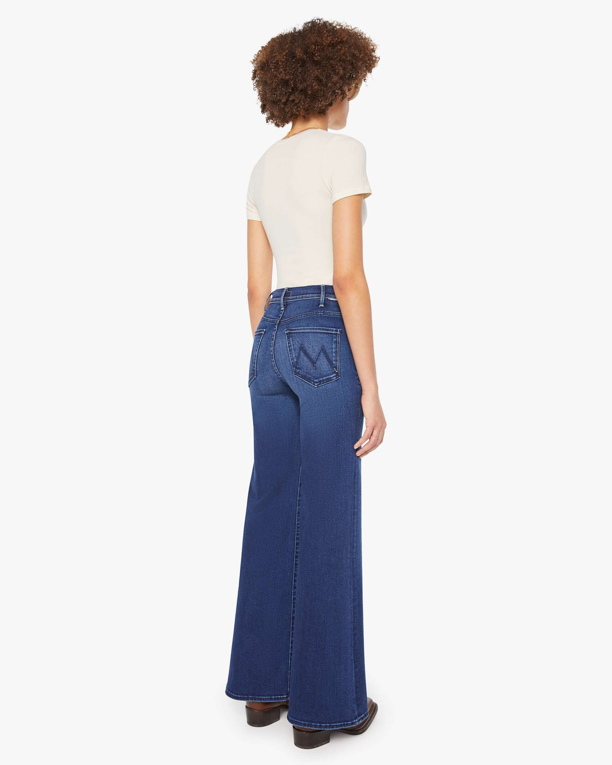 Person wearing blue jeans and a white top on a white background