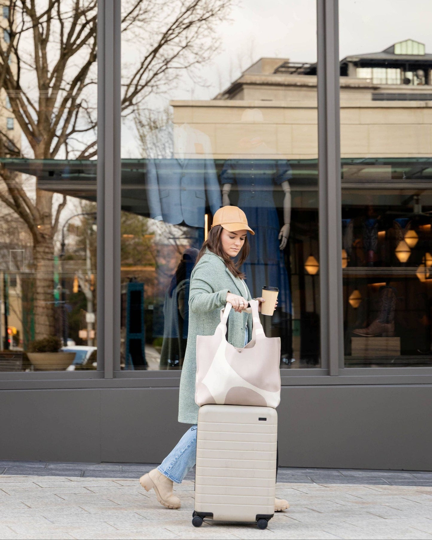 Woman with a suitcase and shopping bag walking outside a building