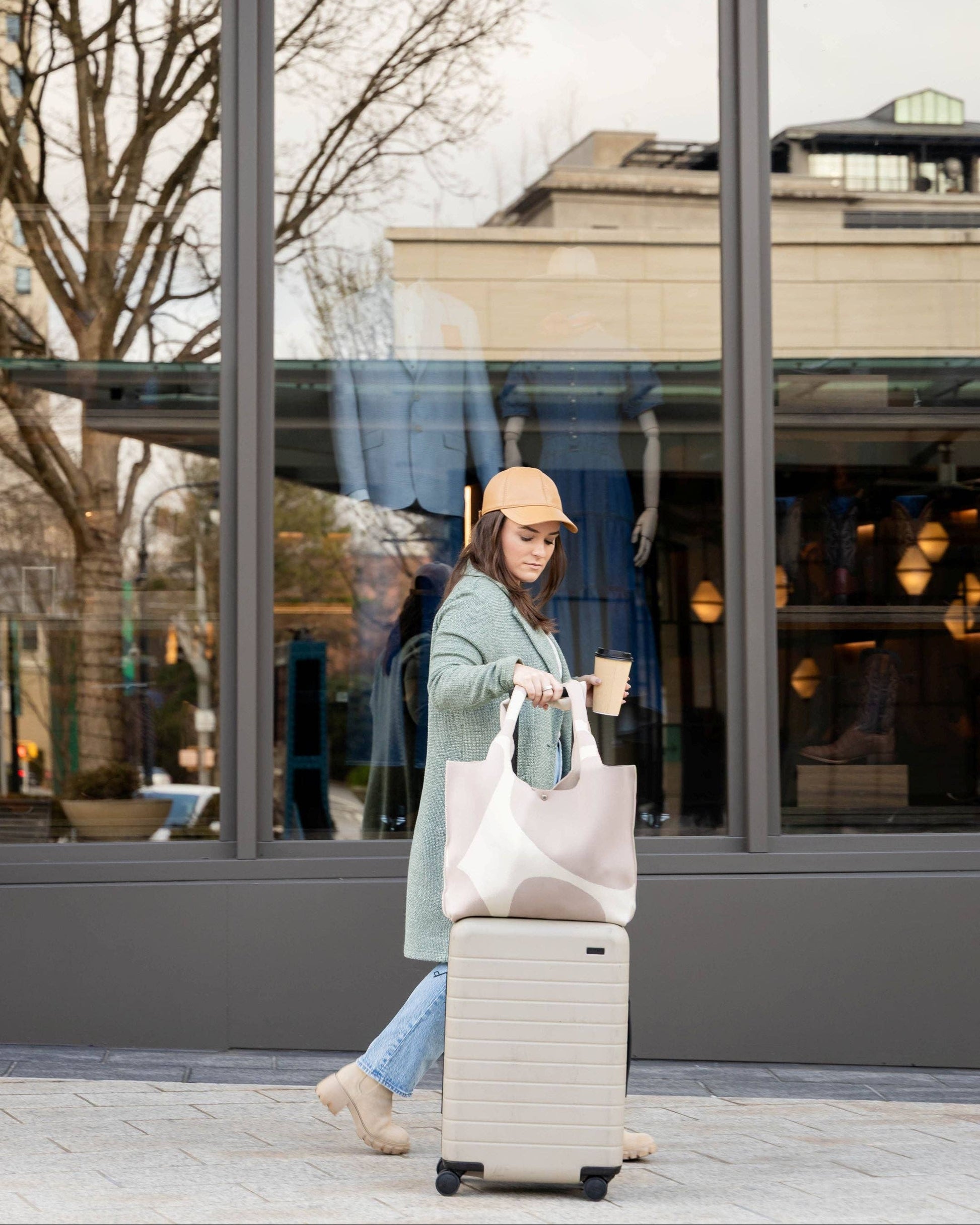 Woman with a suitcase and shopping bag walking outside a building