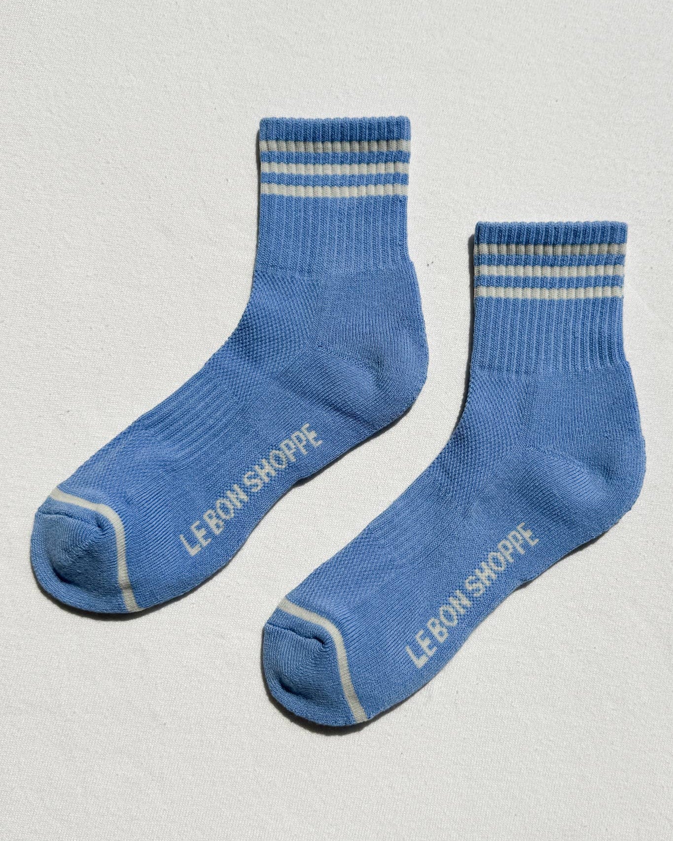 Pair of blue socks with striped pattern and 'LEMON SHOPPE' branding on a light gray background