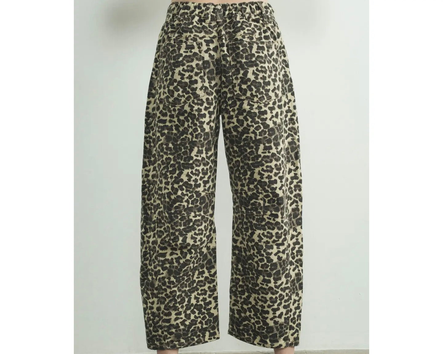 Back view of a model wearing a relaxed fit denim pant in leopard animal print on a white background.