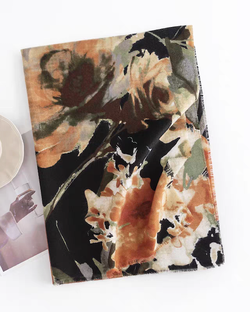 Floral patterned blanket on a white surface with a magazine and cup.