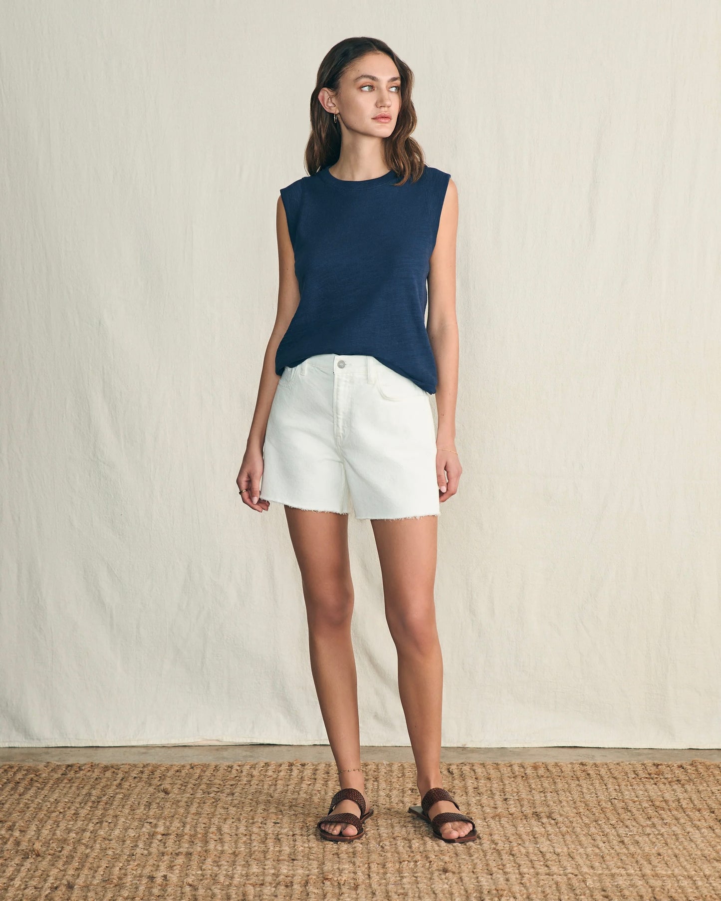 Model wearing Faherty Sunwashed Slub muscle tank in navy wearing white shorts on a white background