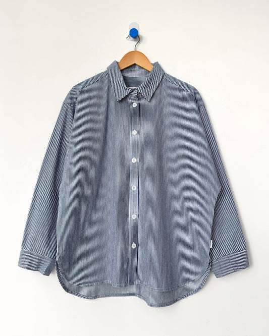 Blue striped shirt on a wooden hanger against a white background