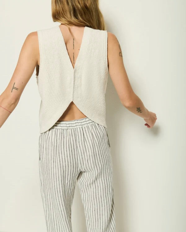 Back view of the Nation Eliza Sweater Tank in striped pants standing in front of a white wall