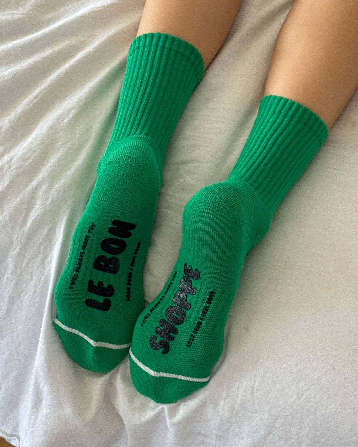 Green socks with text worn on a white bed sheet