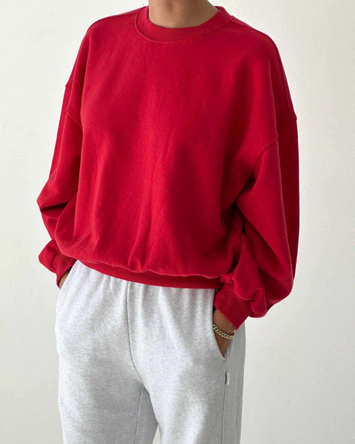 Person wearing a red sweatshirt and gray pants on a white background