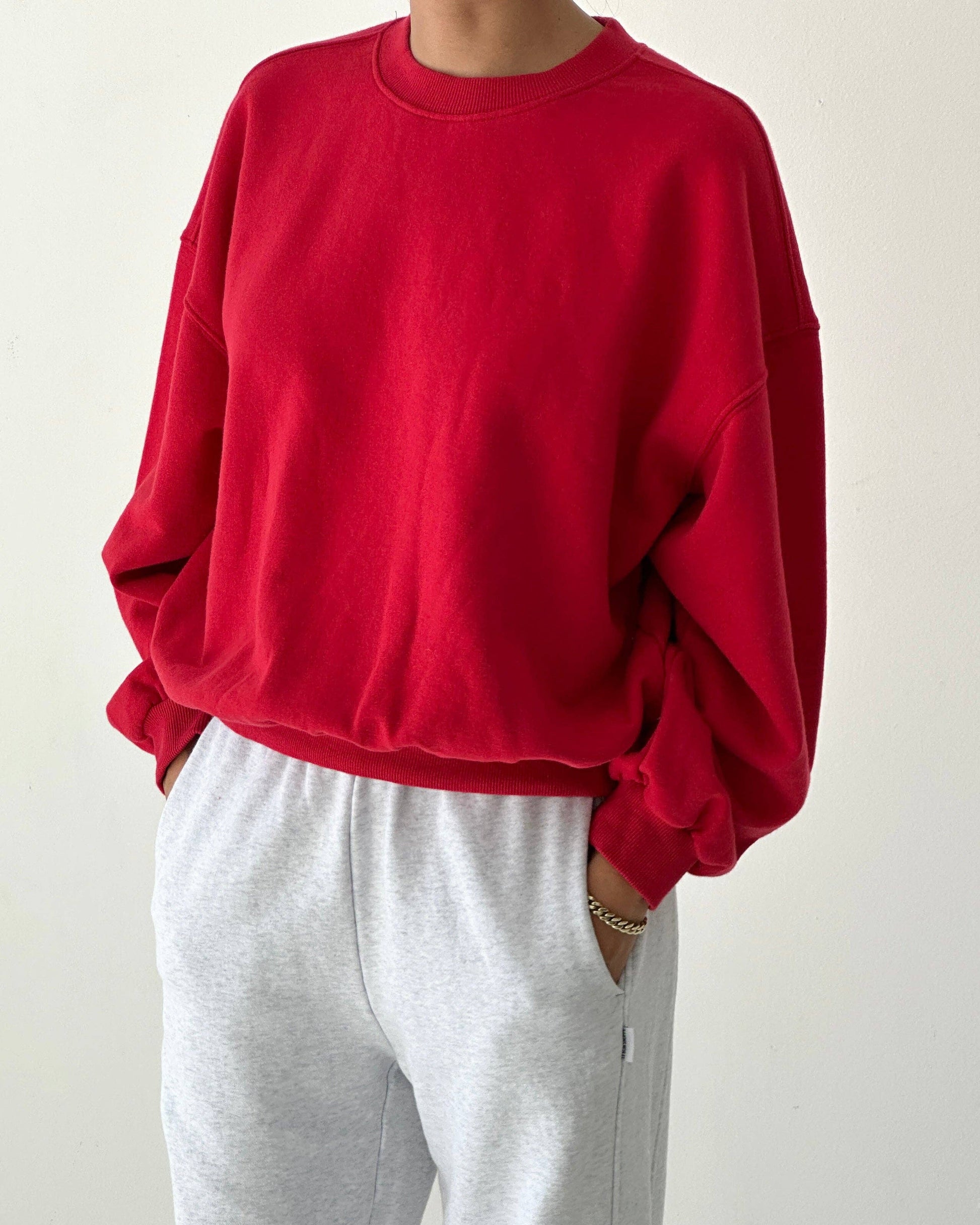 Person wearing a red sweatshirt and gray pants on a white background