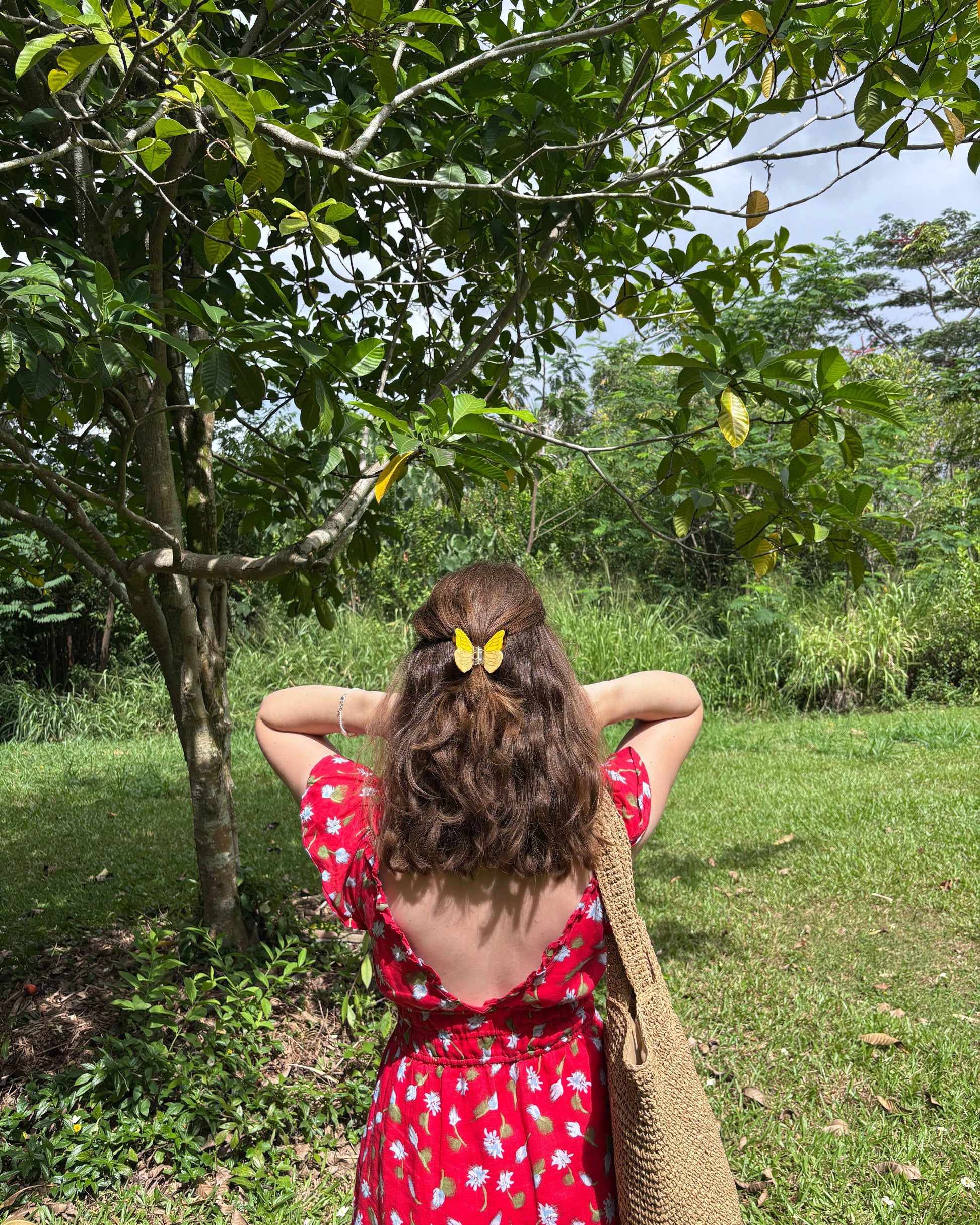 Woman in a red dress with a butterfly in a lush green garden