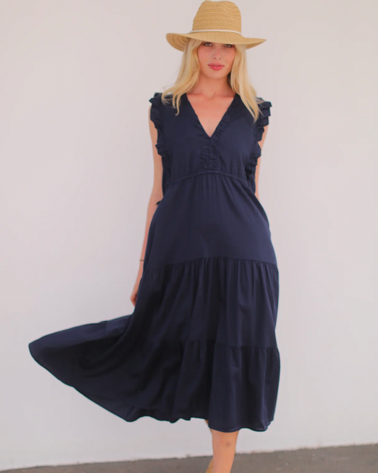 Model wearing Stark X Poplin Levi Dress in Navy wearing a straw hat on a white background