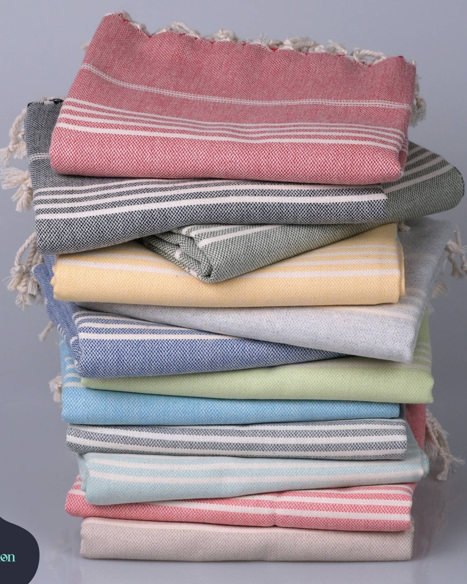 Stack of folded towels in various colors on a gray background