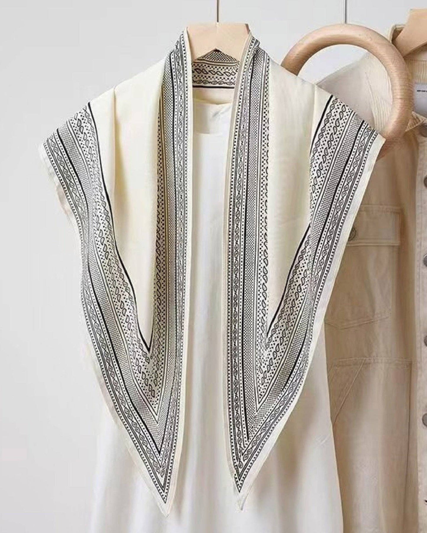 White shirt with black embroidery on a wooden hanger against a white background