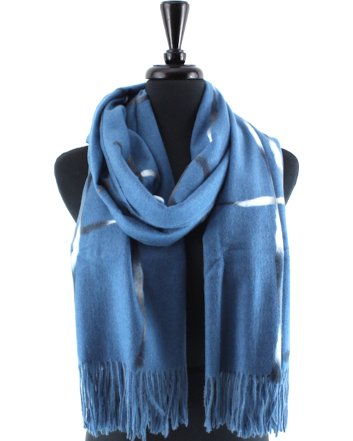A blue knit scarf with white tie-dye style stripes and fringed ends, displayed on a black mannequin torso against a plain white background.