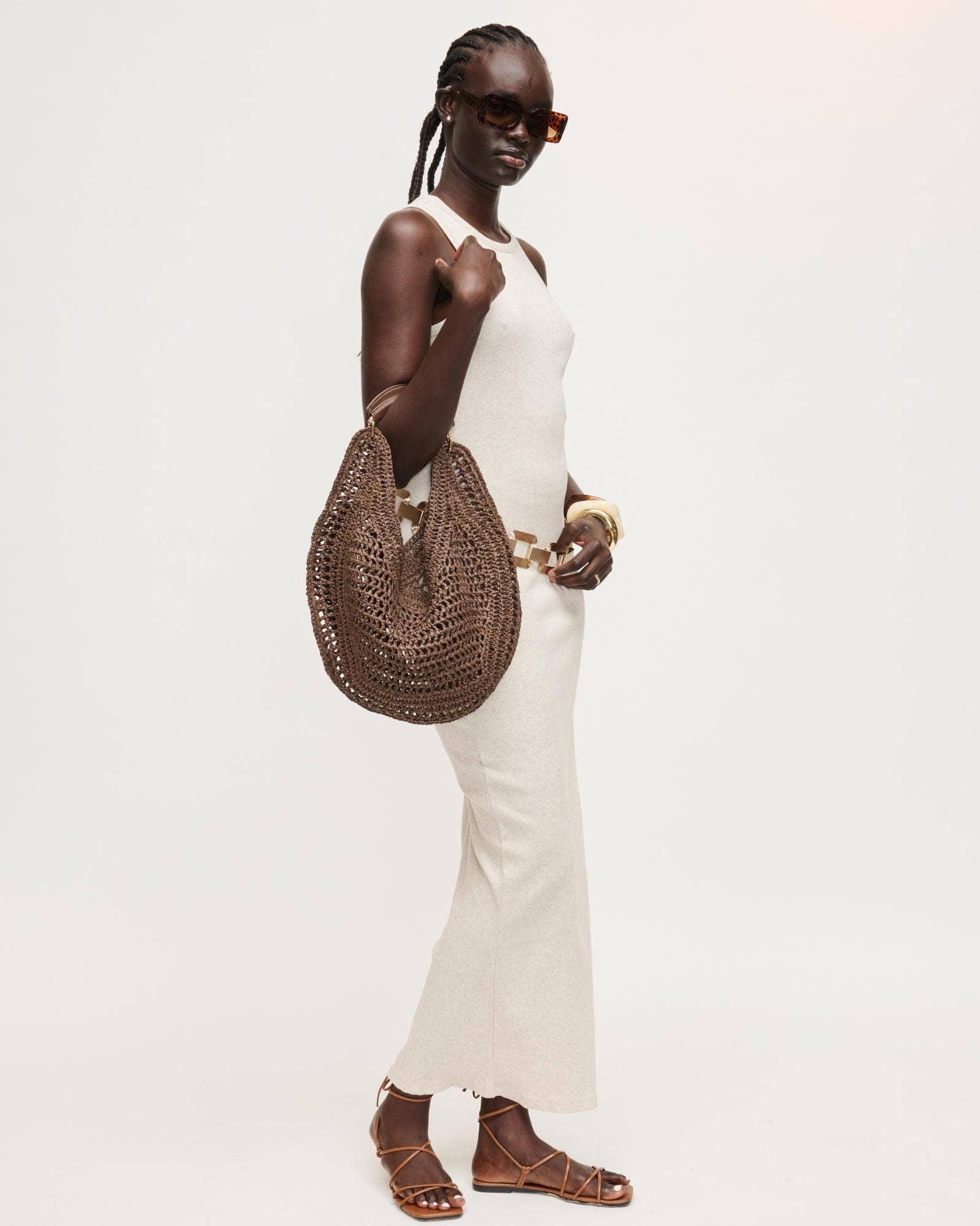 Woman holding a woven handbag against a plain background