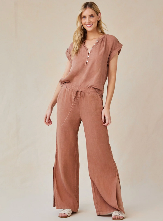 Model is wearing Bella Dahl Side Slit Wide Leg Pant in Terracotta Brown with matching top and white sandals on a off-white background