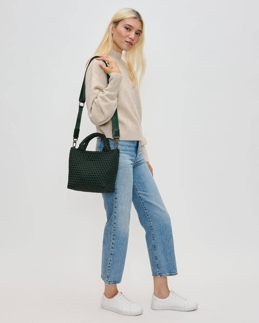 Woman holding a black handbag against a plain background