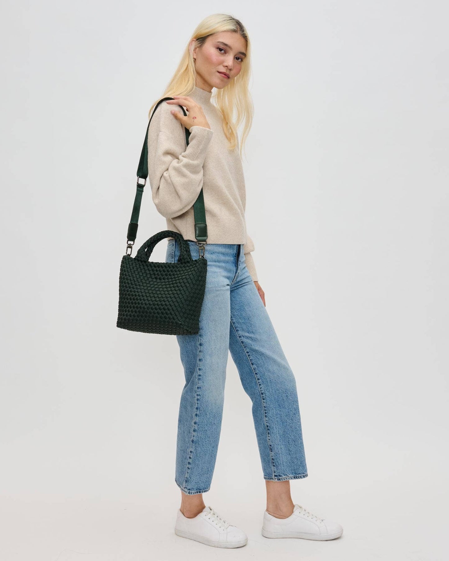 Woman holding a black handbag against a plain background