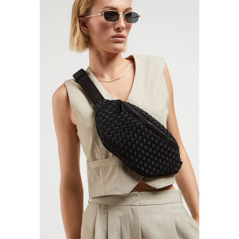 Model wearing Sol & Selene Aim High Woven Neoprene Belt Bag wearing brown tank top and sunglasses on a white background