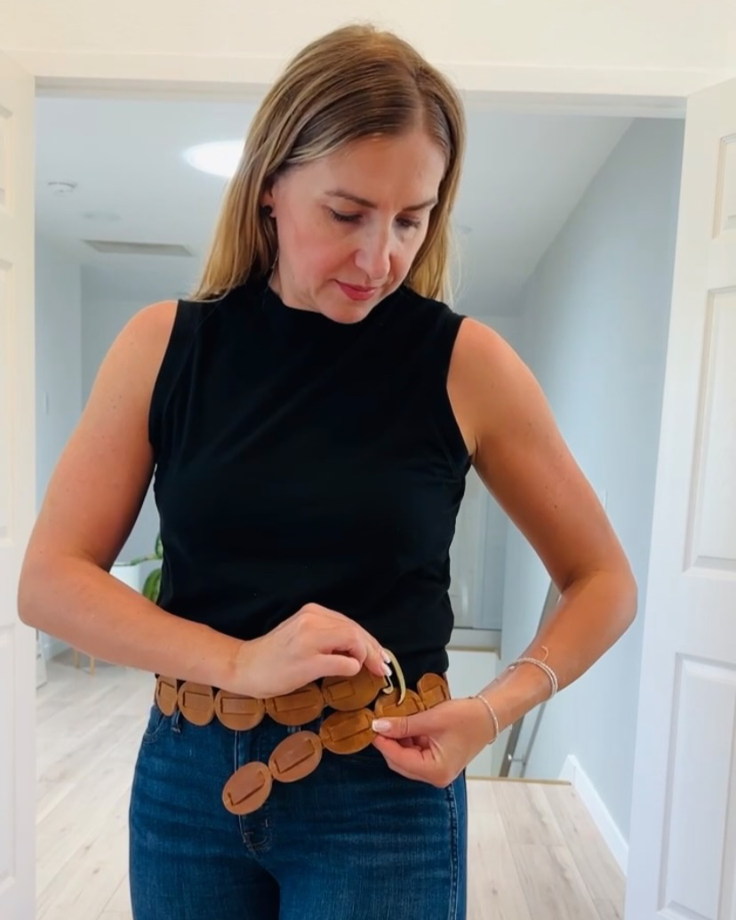 Woman adjusting a belt with circular patterns in a room.