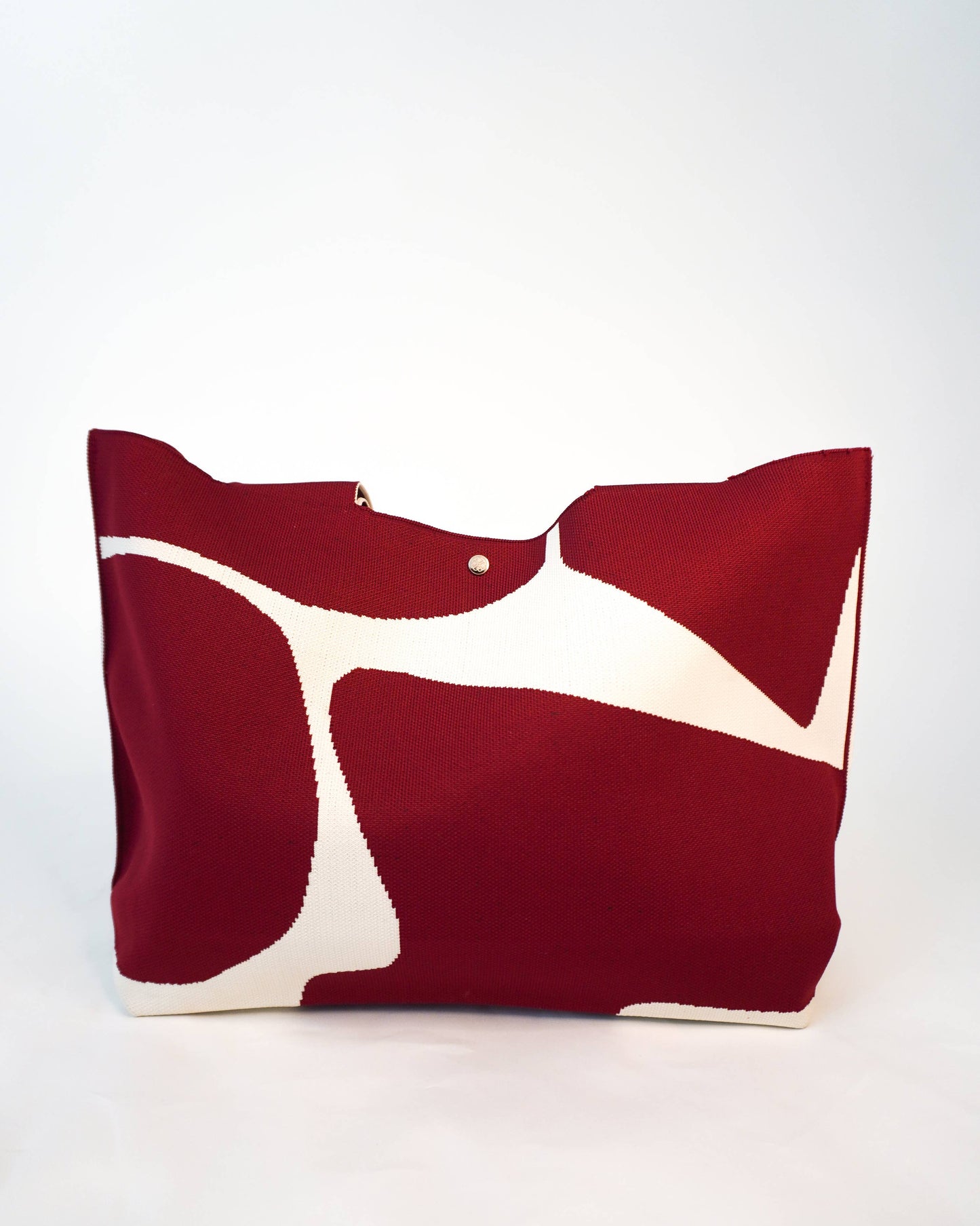 Red and white abstract patterned pillow on a white background