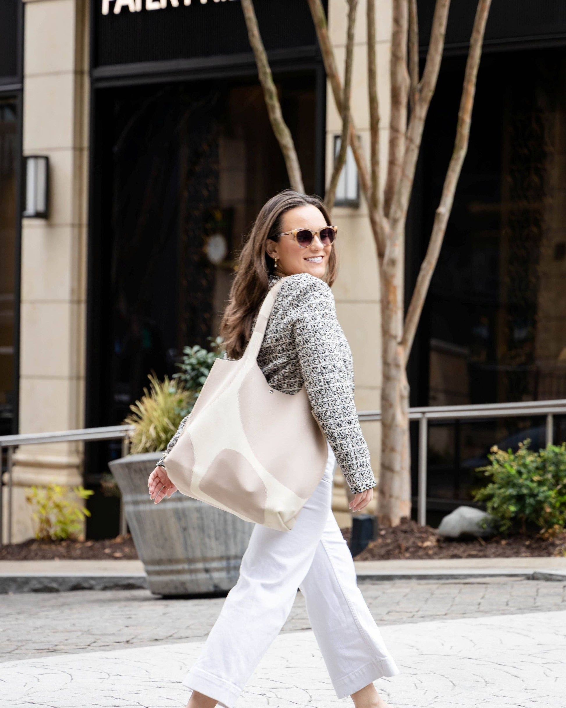 Woman walking on a sidewalk in front of a Patek Philippe store