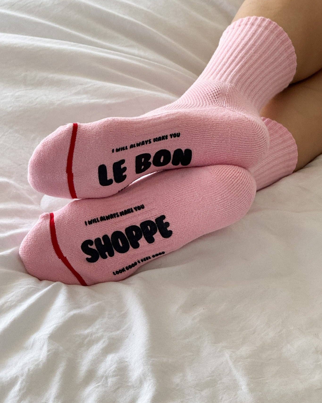 Pink socks with text on a white bed
