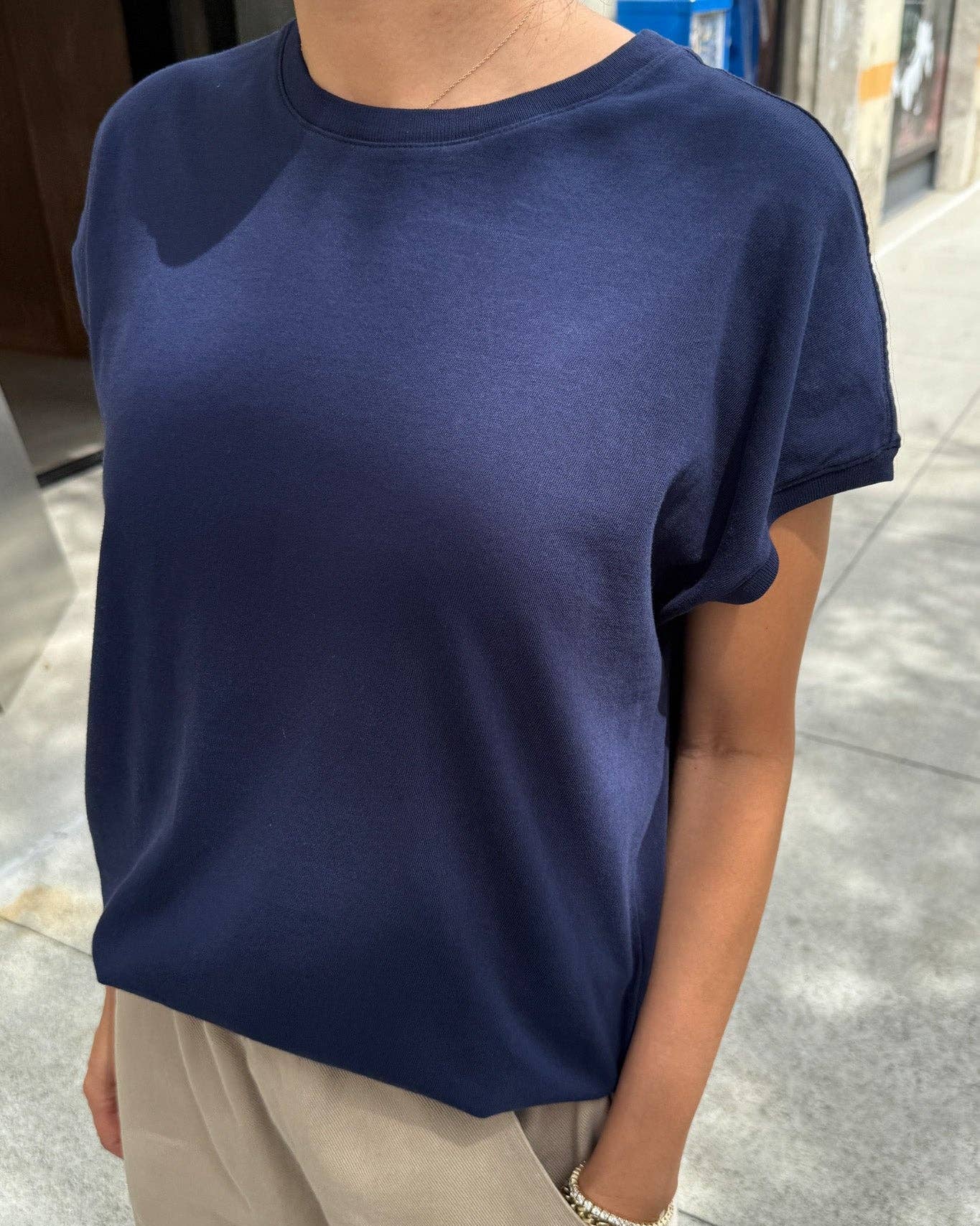 Person wearing a navy blue t-shirt and beige pants on a sidewalk.