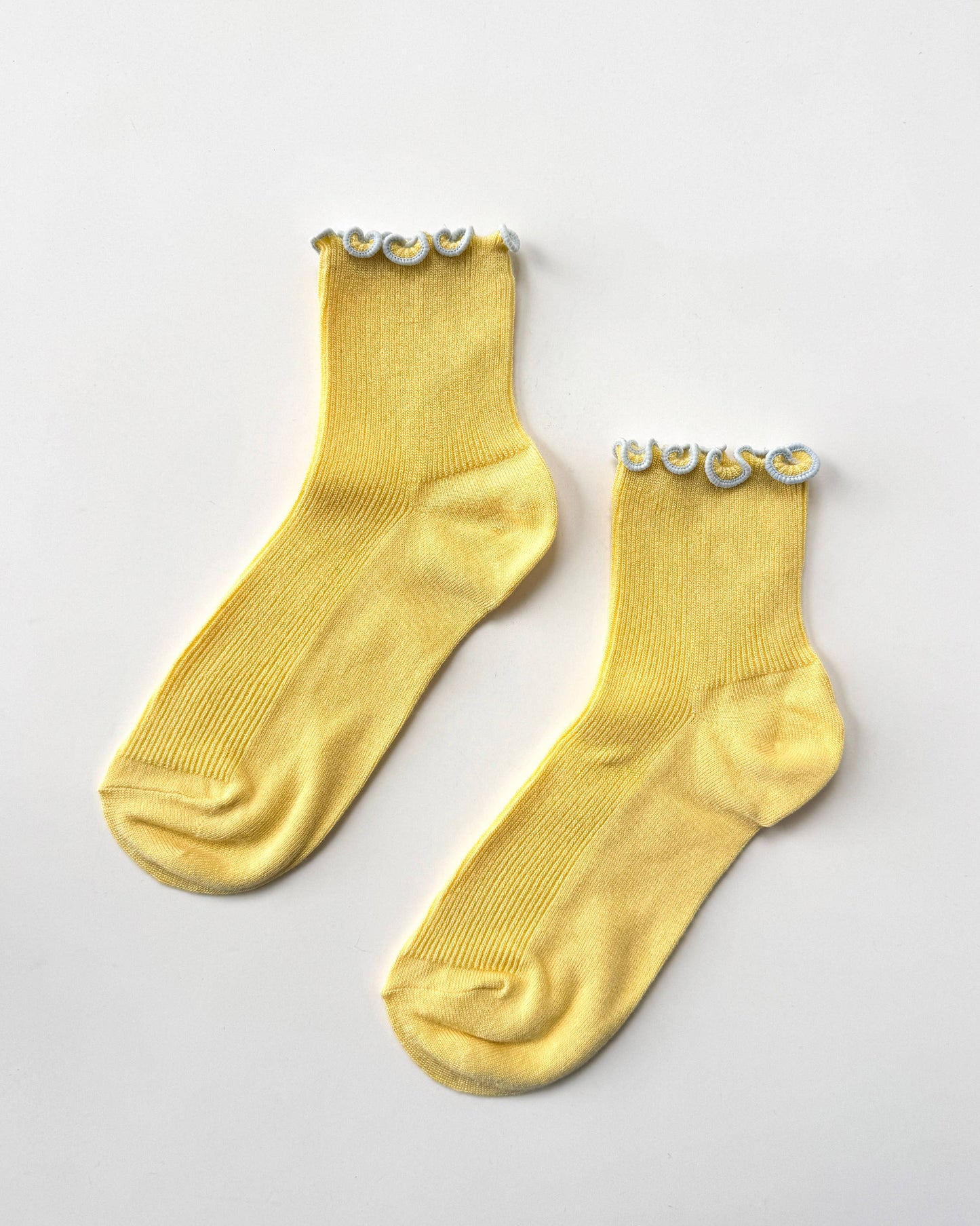 Pair of yellow socks with decorative elements on a light gray background