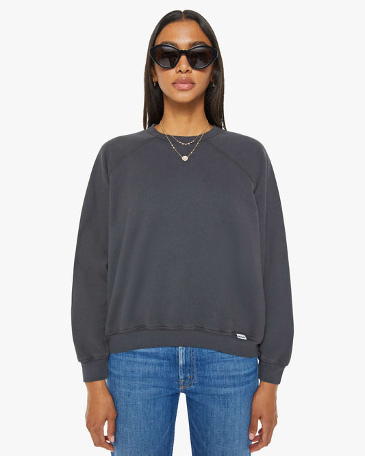 Woman wearing a dark gray sweatshirt and blue jeans on a white background