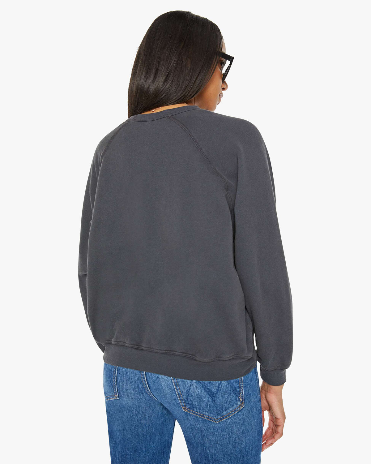 Person wearing a dark gray sweatshirt and blue jeans on a white background