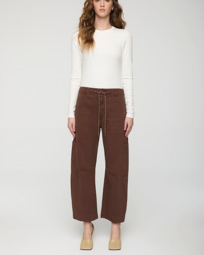 Woman wearing a white long-sleeve top and brown wide-leg pants on a white background