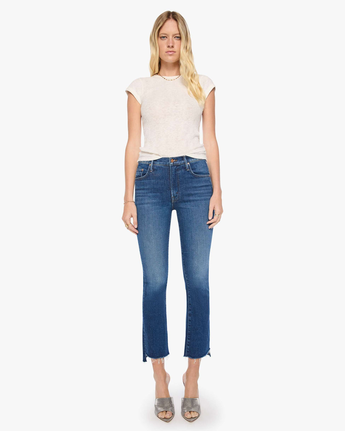 Woman wearing a white top and blue jeans on a white background