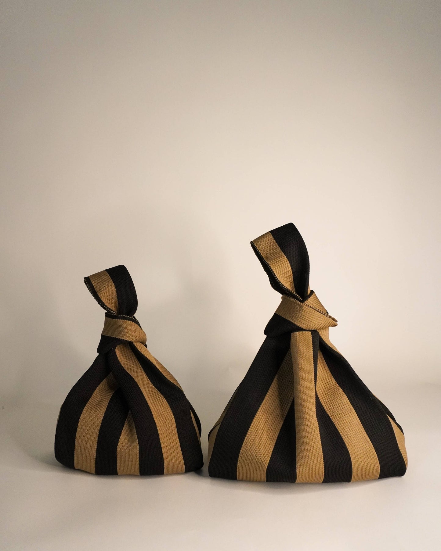 Two black and gold striped fabric cones on a plain background