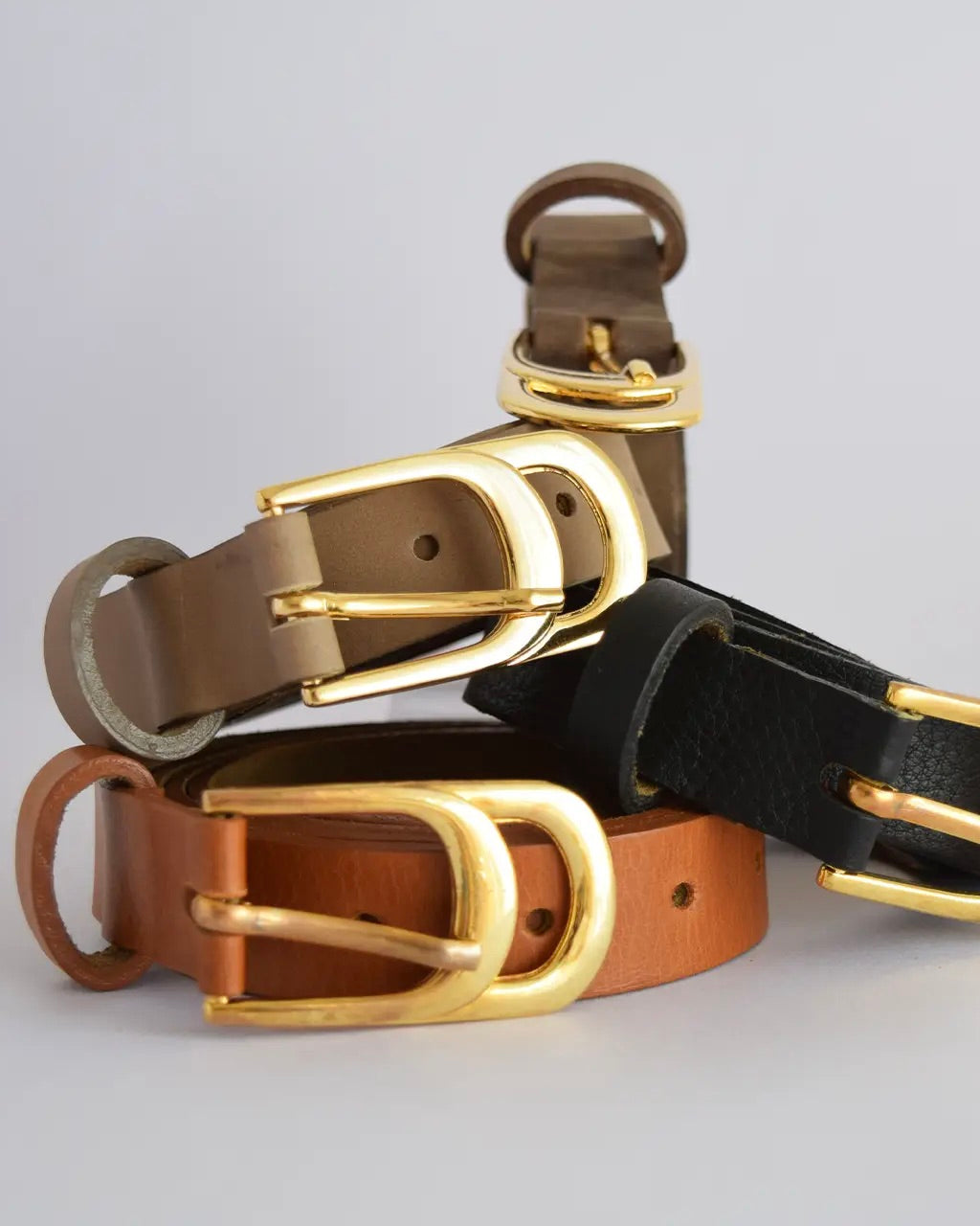Close up photo of the Ada Infinity leather belt in various colors in front of a white background