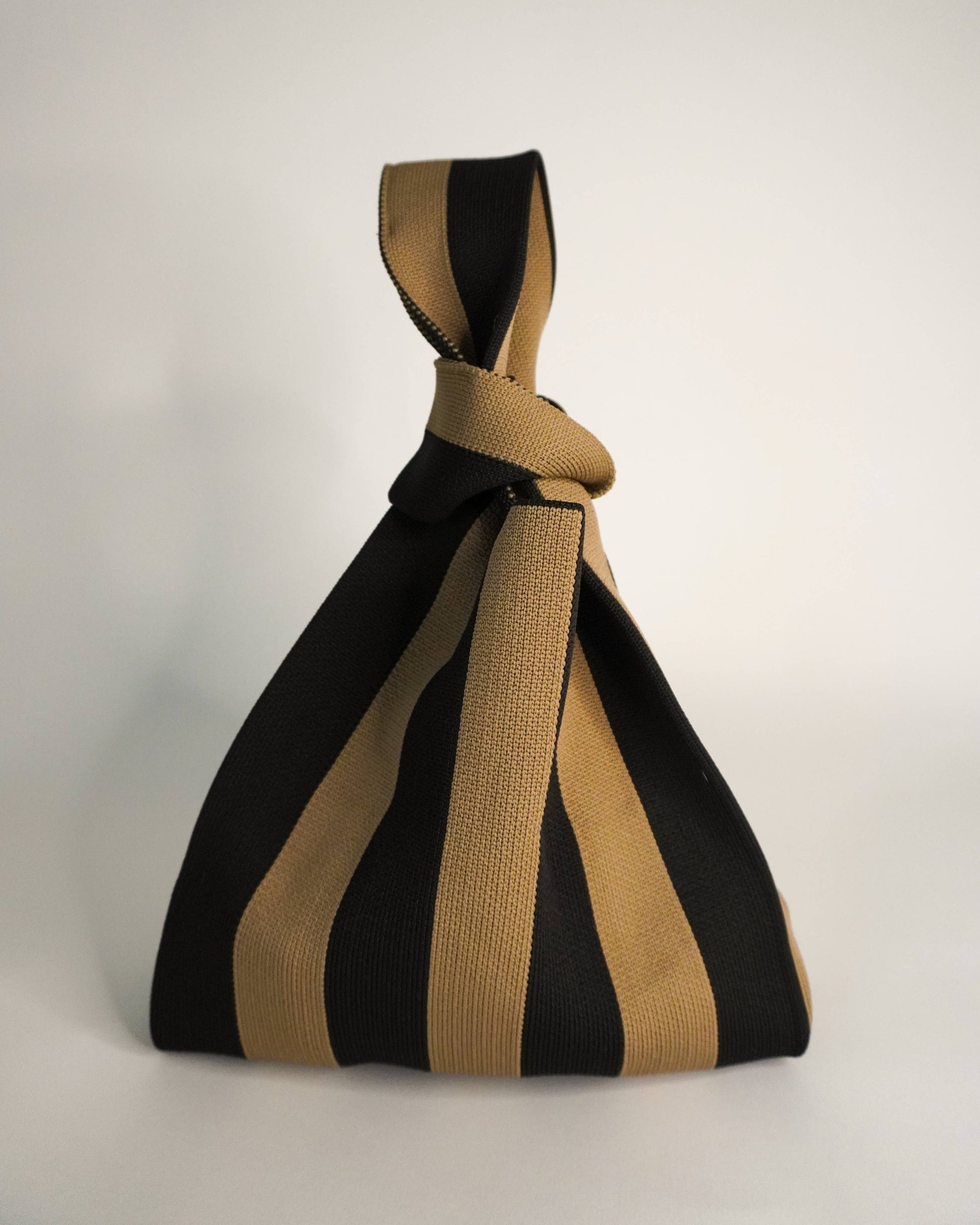 Black and beige striped bag with a knot on a white background